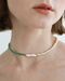 Necklace of pearls and small green stones with a rectangular pearl