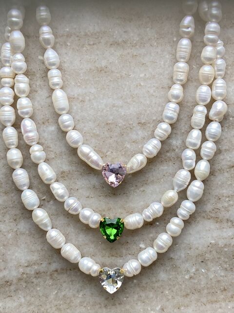 A pearl necklace with a green heart