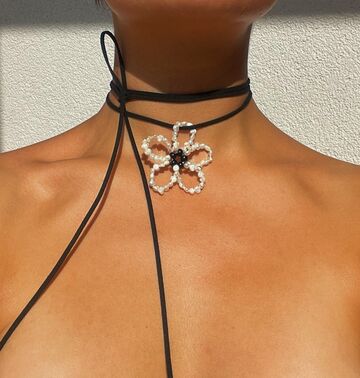 A white flower with pearl on a black string